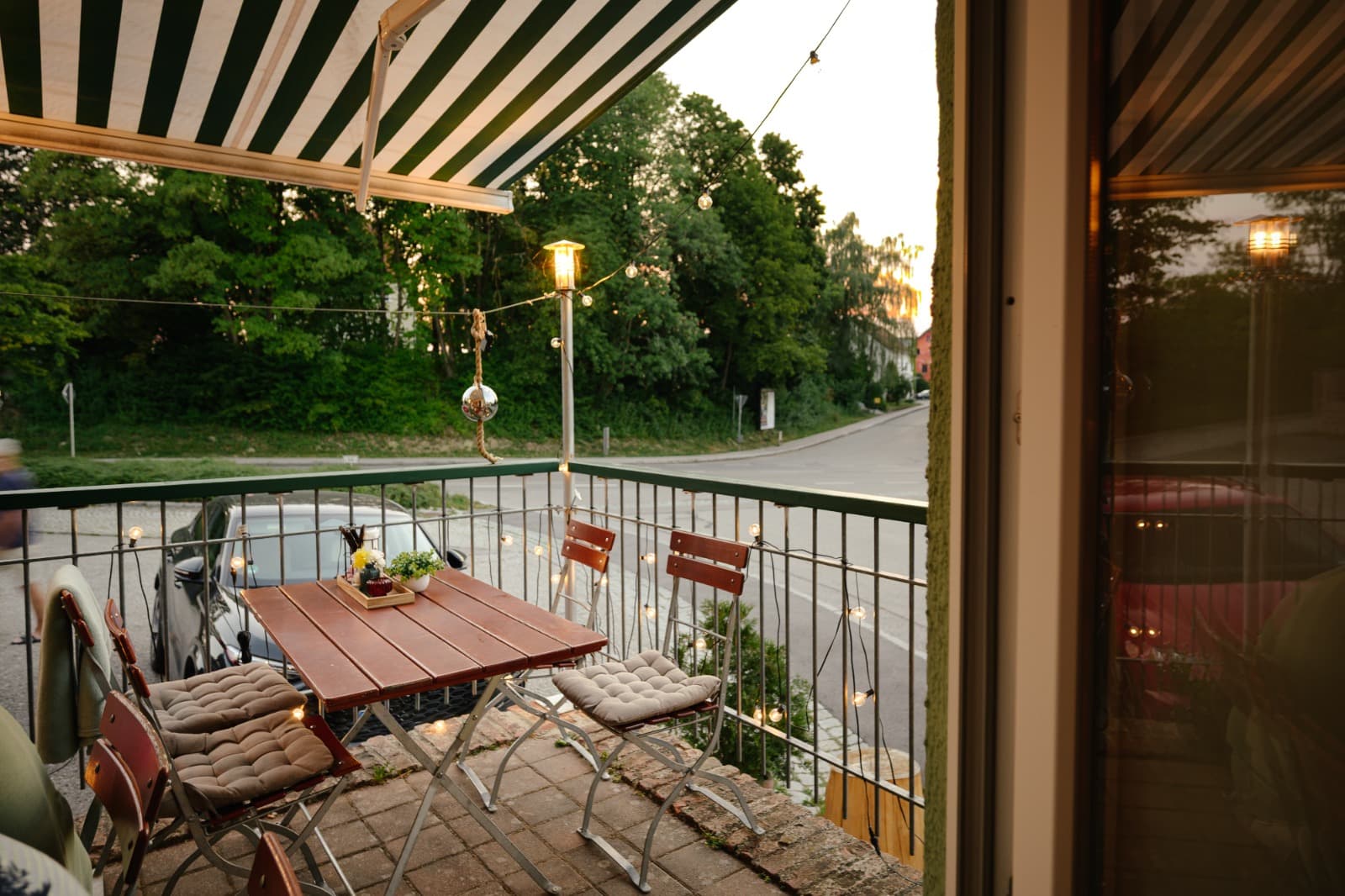 Balkon-Terrasse mit Bistrotischen und Lichterketten bei Dämmerung